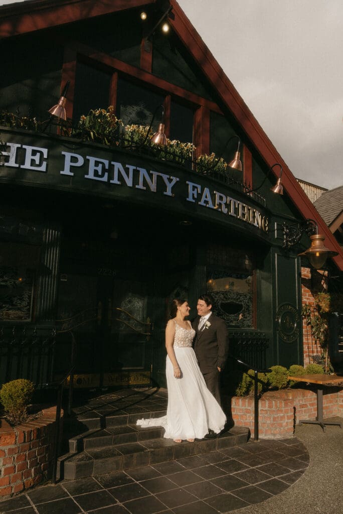 couple standing outside of penny farthing pub on the black tile steps
