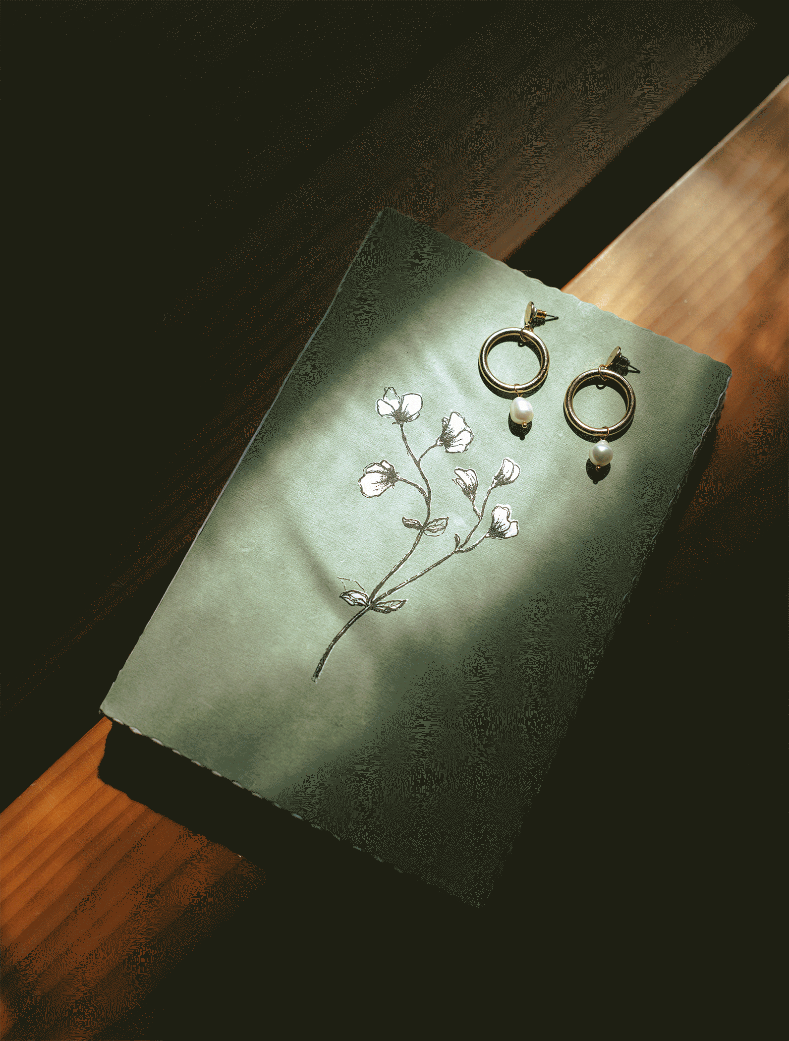 A gif shows sunlight dancing on wedding jewelry atop a green book in a detail shot by BC elopement photographer 