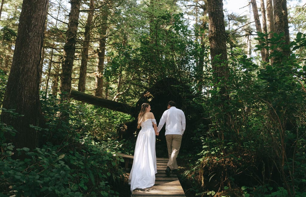 Newlyweds walk hand-in-hand through the forest after their pacific sands beach resort wedding