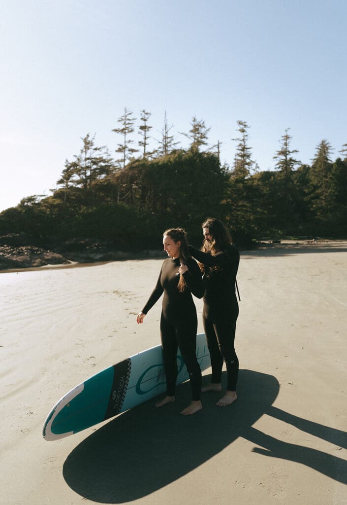 A groom helps his new bride with her wet suit before surfing at pacific sands beach resort tofino bc 