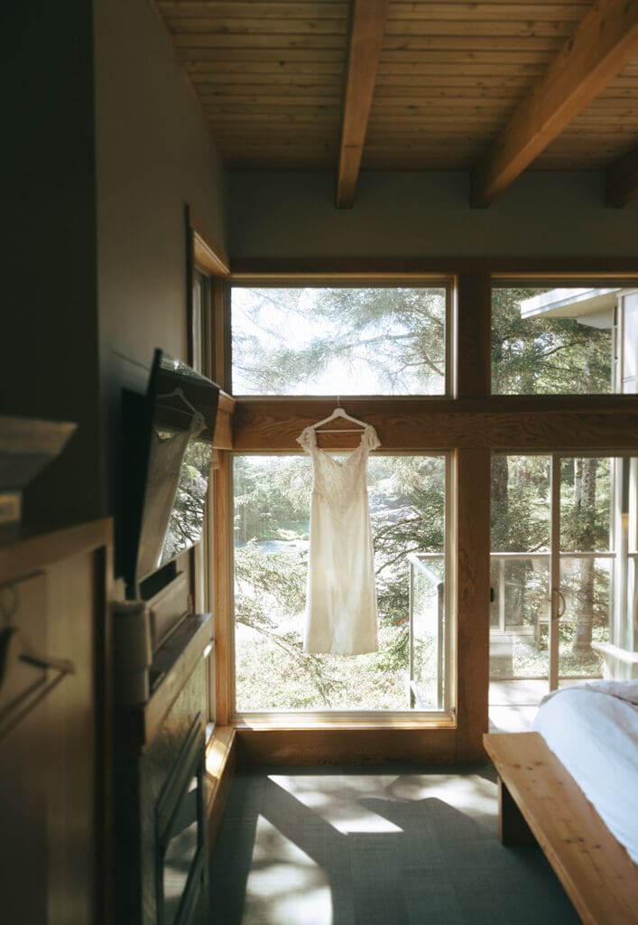 A wedding dress hangs in the window in this photo taken at an elopement held at pacific sands beach resort tofino british columbia