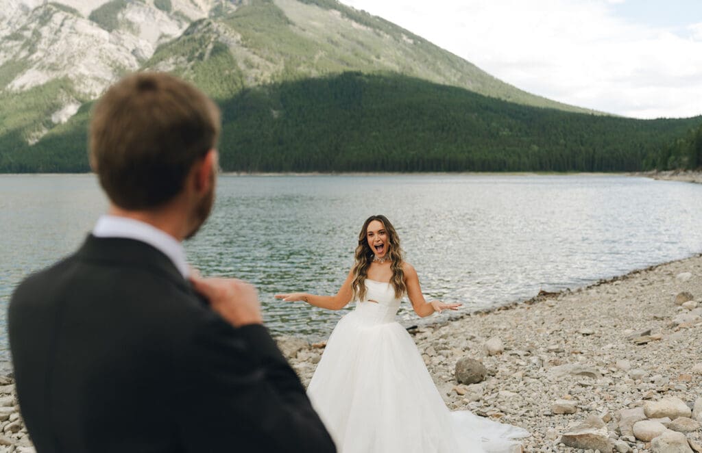 A first look is captured next to the shoreline at a Banff wedding 