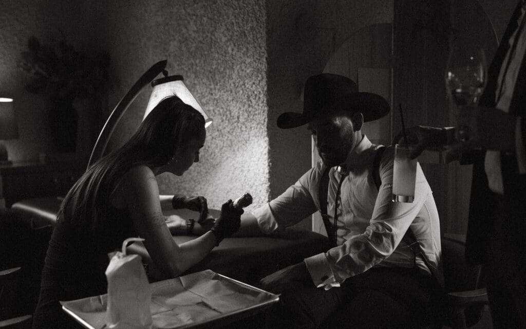 A groom receives a tattoo from an artist hired for his Banff wedding reception at Bluebird Restaurant 