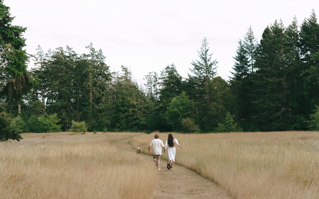 A couple hold hands & run alongside their dogs during engagement photoshoot vancouver