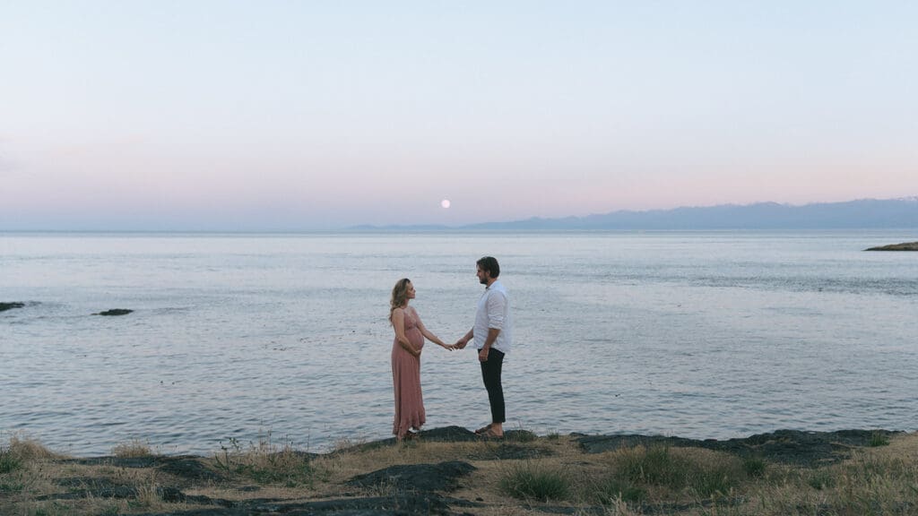 Couple admiring the full moon overlooking the mountains on the beach on Vancouver Island engagement photoshoot location