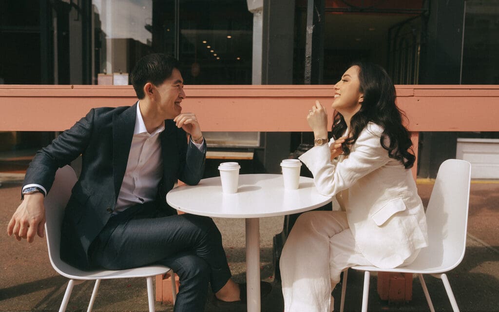 A couple laugh at a cafe in downtown Victoria during vancouver engagement photos