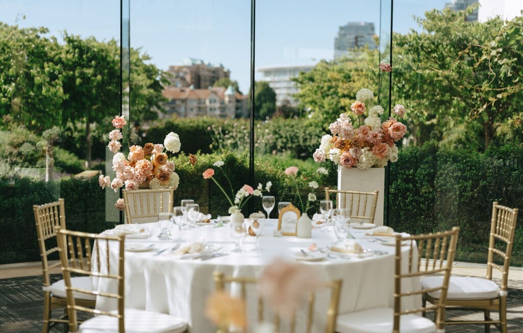 A light & airy inn at laurel point wedding reception table is photographed near tall windows 