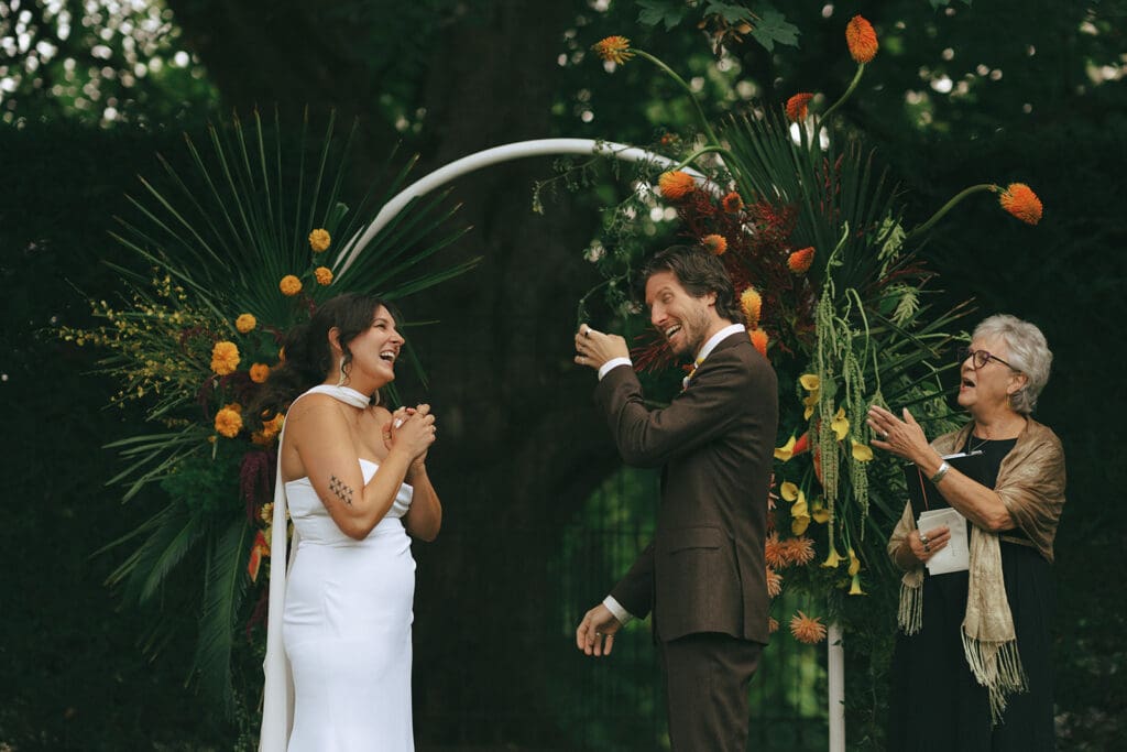 Newlyweds smile beneath a spray of orange florals at their Hatley Castle wedding