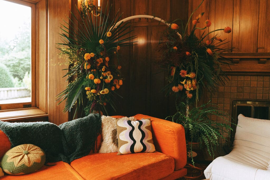 An orange sofa and 1970s decor is photographed before a retro inspired Hatley Castle wedding 