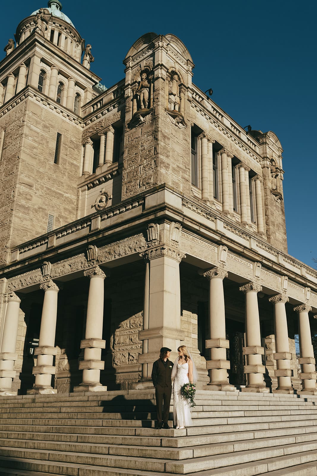 bride and groom standing on the steps of the Parliament Building in Victoria