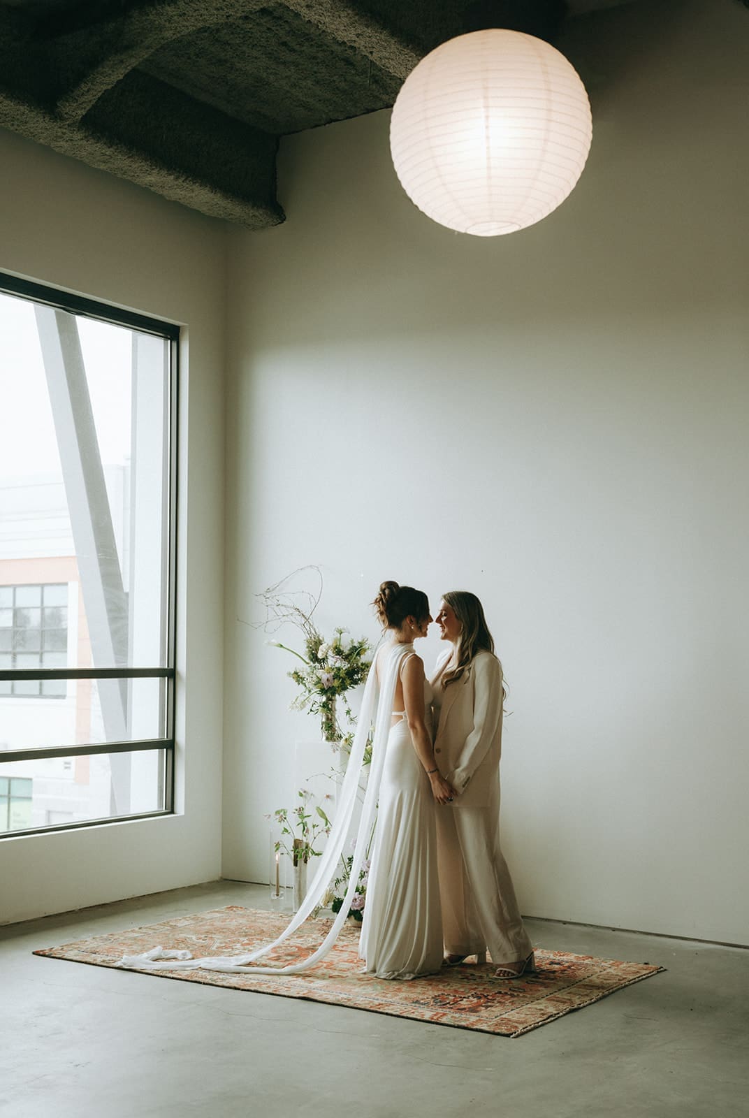 two brides facing each other and holding hands inside modern studio in downtown Victoria