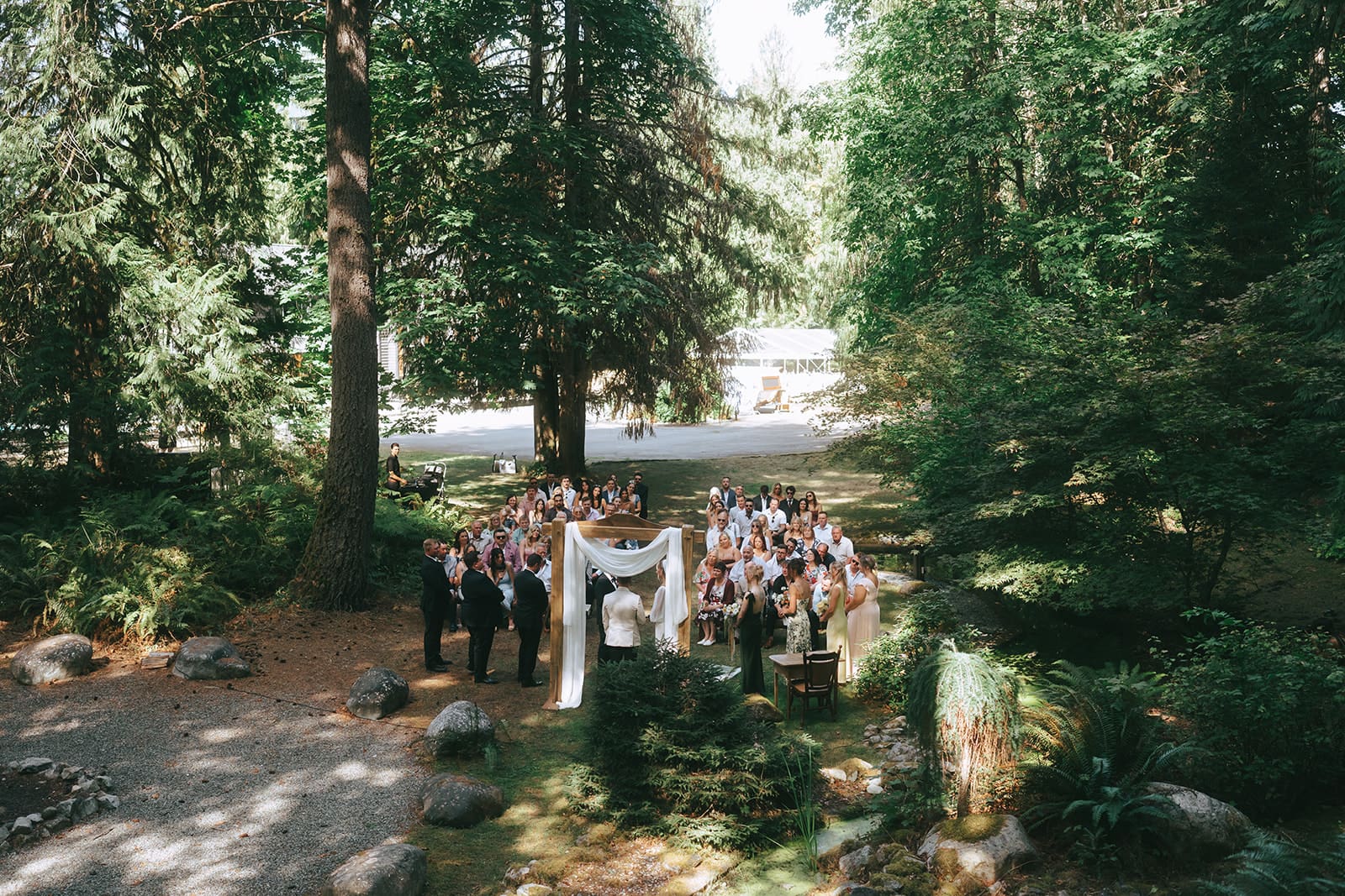 far away shot of wedding ceremony in the forest at West Coast River Lodge